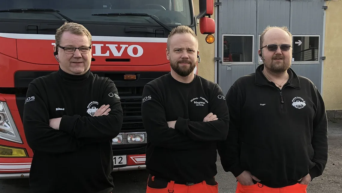 tre bärgare framför bärgarfordon