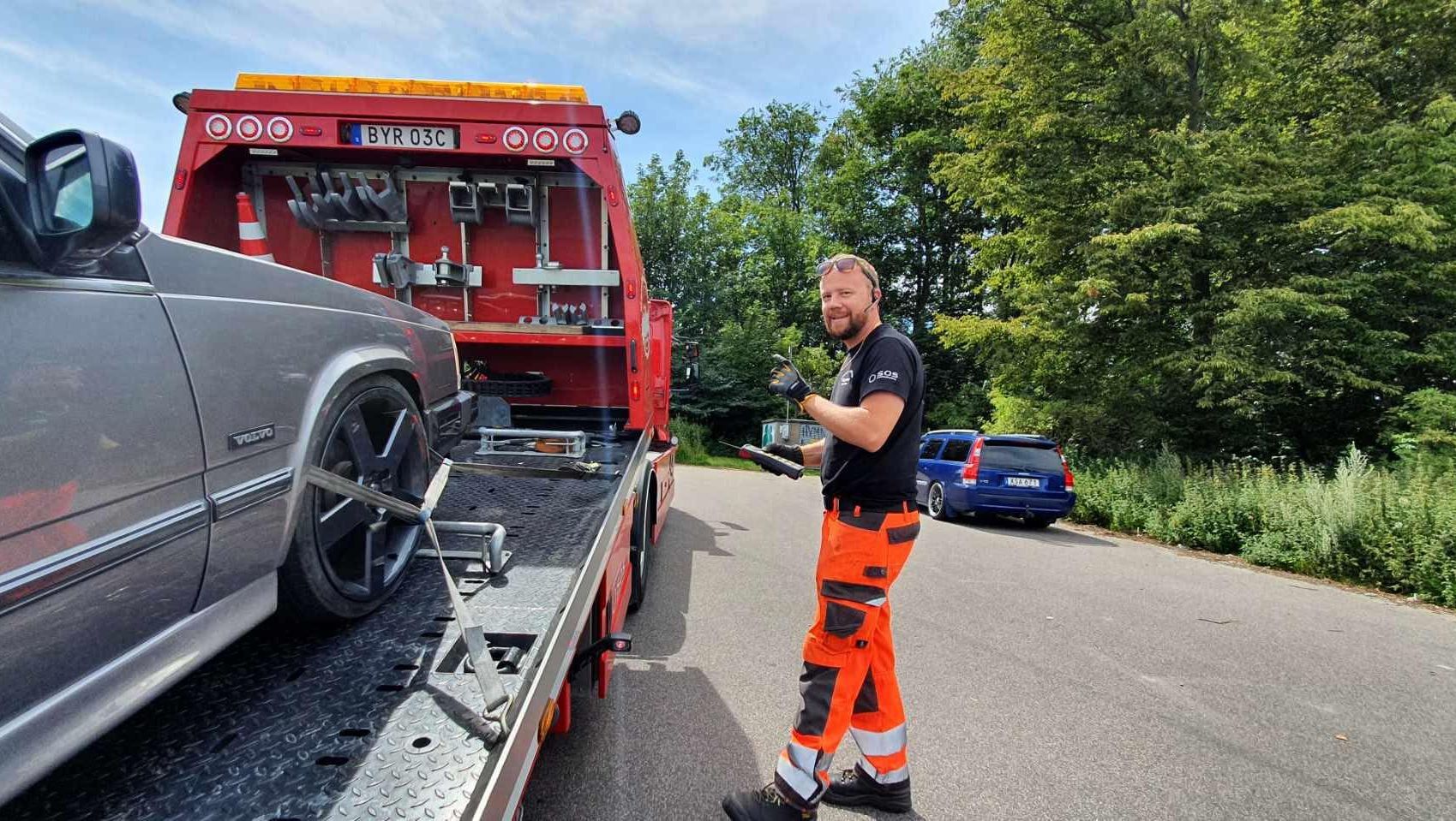 Bärgare framför flaket med bil på bärgningsbil